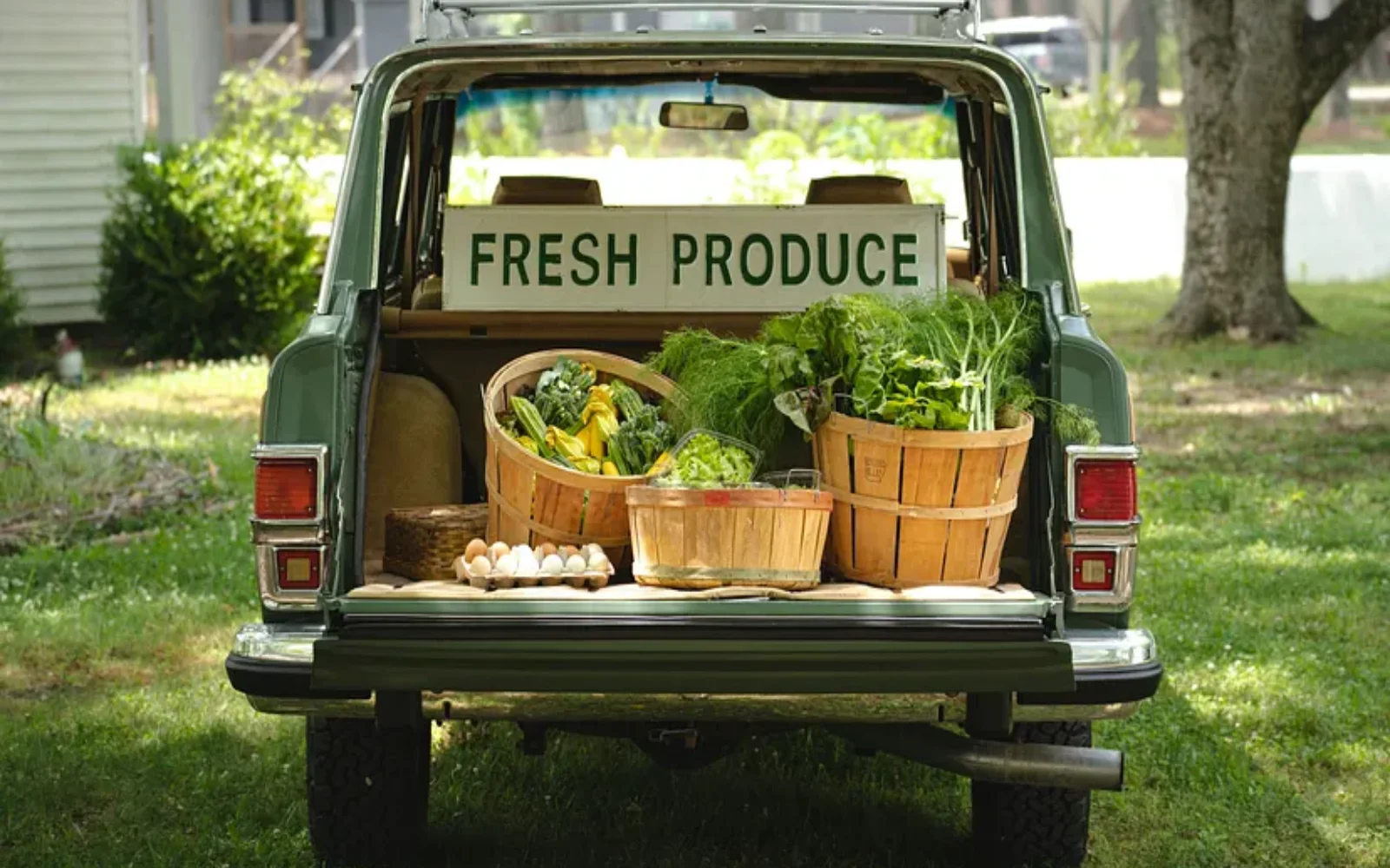 A vintage SUV filled with baskets of fresh produce